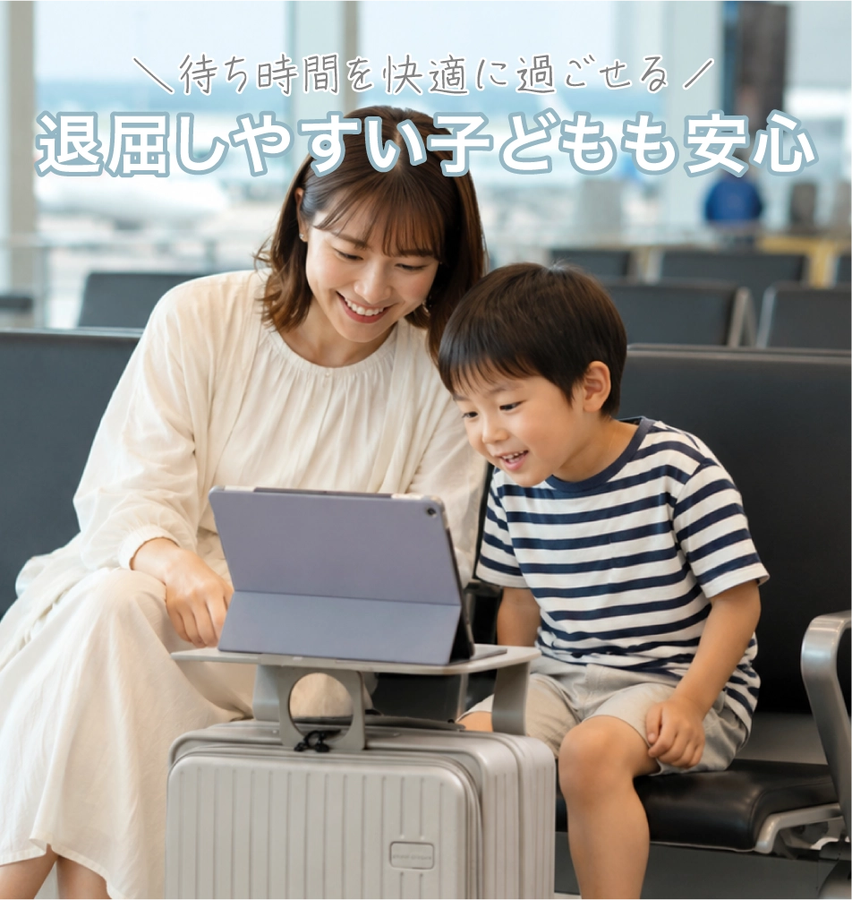 母親と息子がスーツケースのテーブルの上にiPadを置いて空港で時間を潰している写真